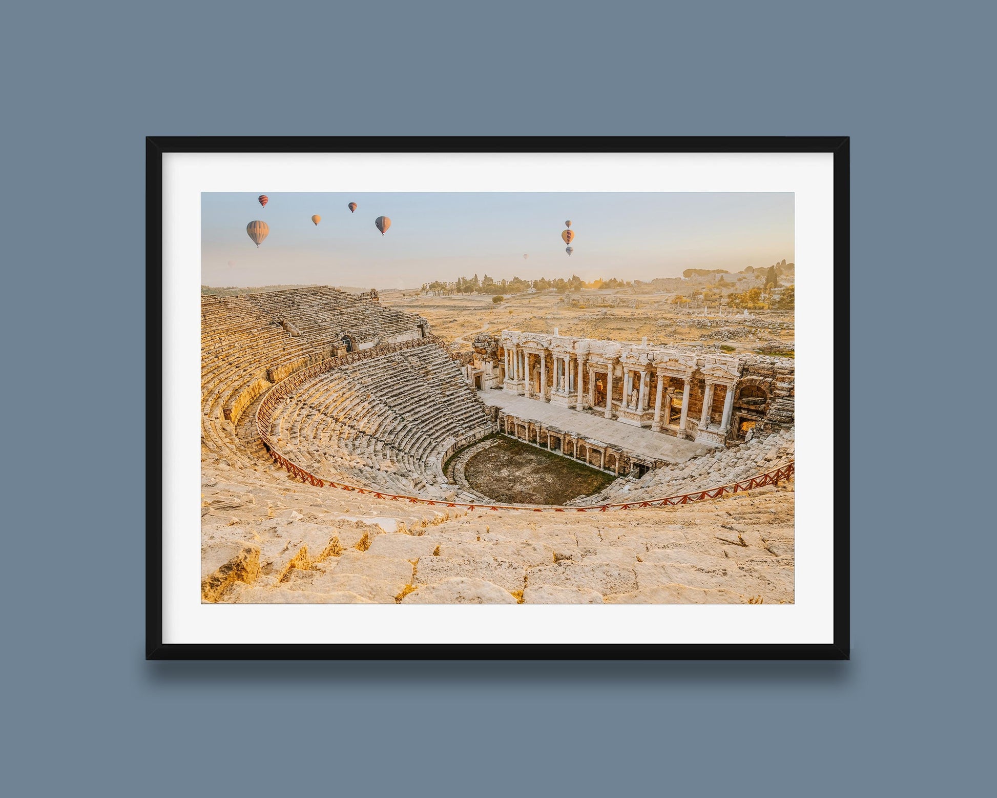 Black framed wall art featuring Hierapolis Ancient Theatre at sunrise, with stone amphitheater seats, Roman ruins, and hot air balloons in a pale morning sky.