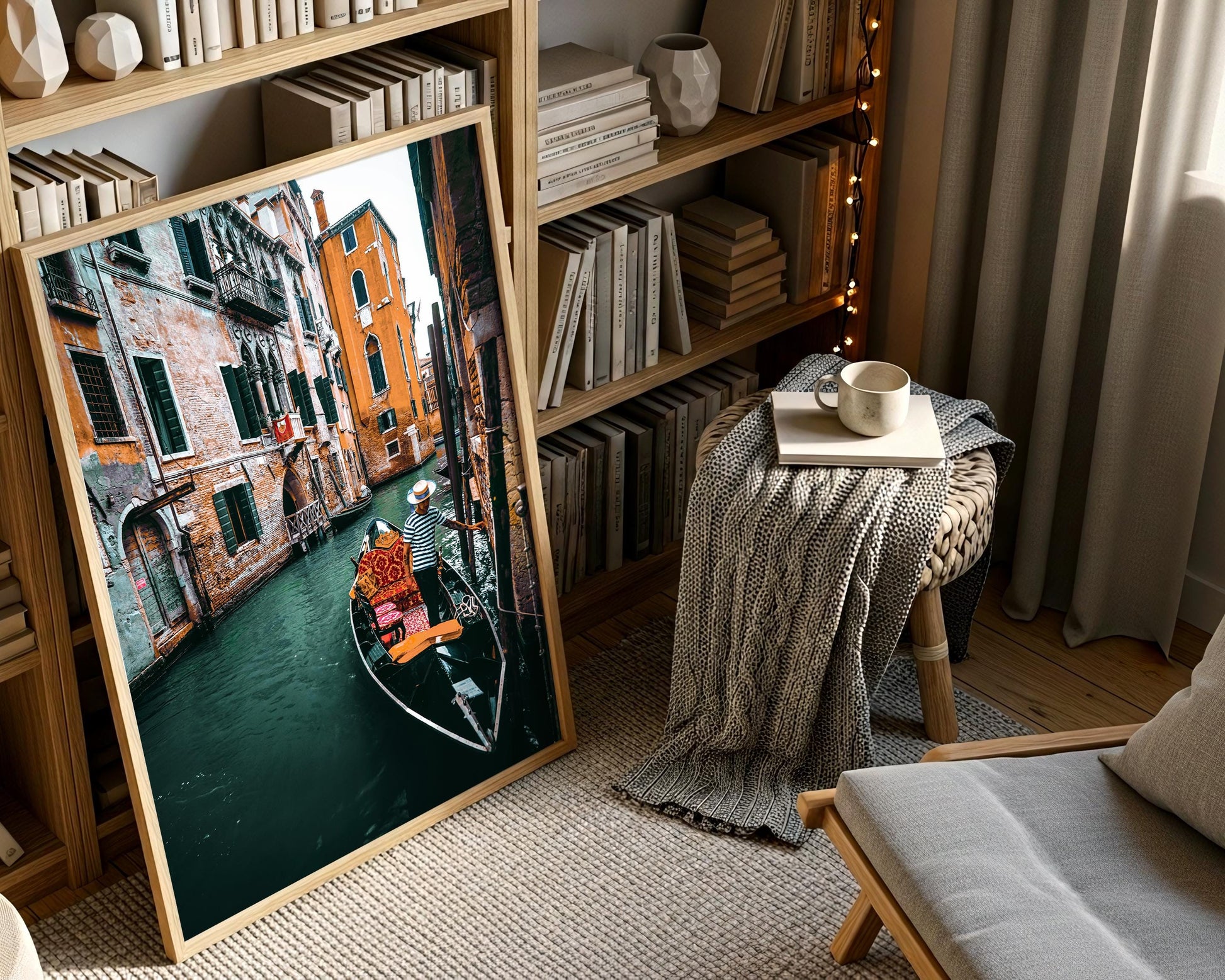 Large framed Venice canal photograph leaning near a bookshelf with soft string lights, cozy textiles, and warm indoor lighting.